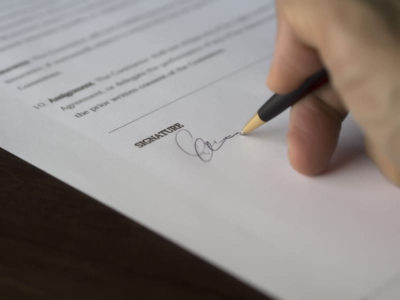 Mano firmando un documento sobre la línea de firma